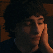 a close up of a person 's face with their hand on their face
