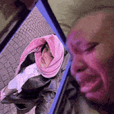 a woman wearing a pink scarf is taking a selfie on a cell phone