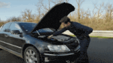a man is looking under the hood of a car