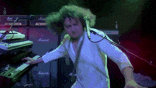 a man in a white shirt is playing a keyboard in front of a marshall amplifier