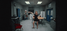 a woman in a black dress is dancing in an office