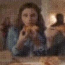 a blurry picture of a woman eating a hamburger in a restaurant .