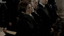 a man in a suit and tie stands in front of bbc