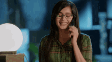 a woman wearing glasses is smiling and talking on a cell phone