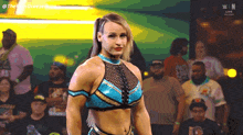 a woman in a blue and gold outfit stands in front of a crowd with the letters w on the bottom