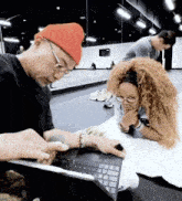 a man wearing a red beanie is looking at a laptop