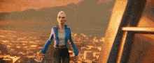 a woman in a blue jacket stands in front of a city .