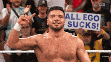 a man in a wrestling ring is holding a sign that says all ego sucks