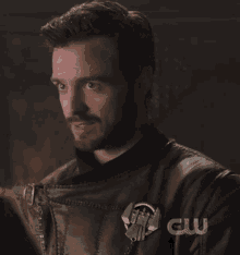 a close up of a man 's face with the cw logo on the bottom right