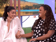 a woman in a polka dot dress holds another woman 's hand