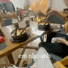 a person is sitting at a table with a bowl of food on it and the words em nha anh written on the bottom