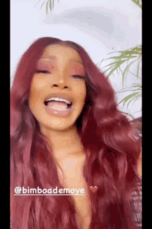 a woman with long red hair is laughing and wearing a wig .