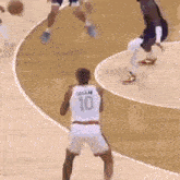 a basketball player wearing a white jersey with the number 10 on it is standing on a court .