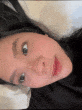 a close up of a woman laying on a bed with her eyes closed