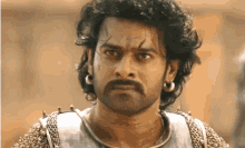 a man with a beard and earrings is wearing a chain mail armor .