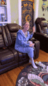 a woman is sitting on a couch in front of a tapestry that has the zodiac signs on it