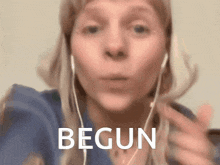 a woman wearing ear buds is making a funny face and says begun