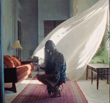 a woman is kneeling down in a living room with a couch and a rug