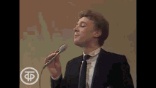a man in a suit and tie is singing into a microphone while wearing a tie .