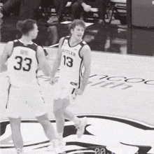a basketball player with the number 13 on his jersey talks to another player