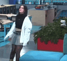 a woman is dancing in a room with a lot of furniture and plants .