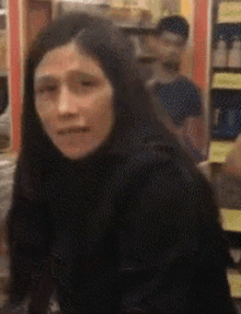 a woman with long hair is standing in front of a store shelf with a coca cola sign on it