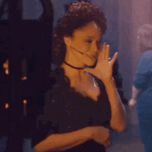 a woman in a black dress and choker is holding a white object in her hand .