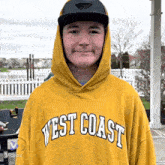 a young man wearing a yellow west coast sweatshirt