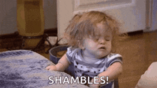 a baby girl is sitting on a couch and making a funny face while saying shambles .