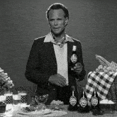 a man holding a bottle of nuka cola in front of a table