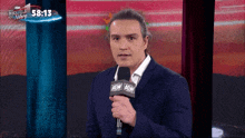 a man in a suit is holding a microphone with aew on it