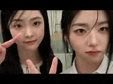 two young women are making a peace sign with their fingers .