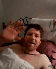 a shirtless man laying in bed with a towel that says club