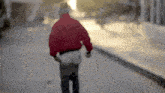 a person in a red jacket walking down a street