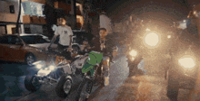 two men are riding motorcycles down a street at night and one has a t-shirt that says ' ny ' on it