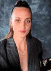 a woman wearing a striped jacket and a necklace is holding a book that says ' harry potter '