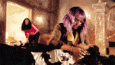 a woman with purple hair is holding another woman 's head
