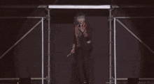 a man with green hair is standing on a stage with his hands up .