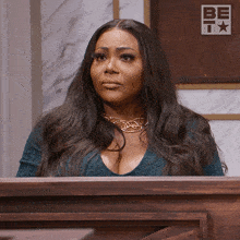 a woman is sitting at a podium with a be t logo behind her