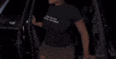 a woman in a black shirt is getting out of a car with the word zeus on the door