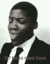 a black and white photo of a man in a suit and tie making a funny face with his eyes closed .