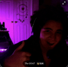 a woman is giving a thumbs up in front of a door that says the goat