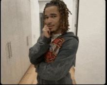 a man with dreadlocks is standing with his arms crossed