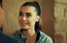a woman with a ponytail is smiling and looking at the camera