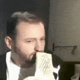 a man with a beard is eating a piece of food from a plate .