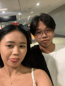 a man and a woman are posing for a picture and the man has glasses on