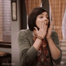 a woman is covering her mouth with her hands and looking surprised .