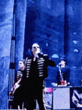 a man singing into a microphone on a stage in front of a crowd
