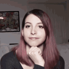 a woman with pink hair has her hand on her chin in front of a map on the wall