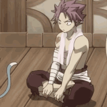 a man with a towel around his neck sits on the floor